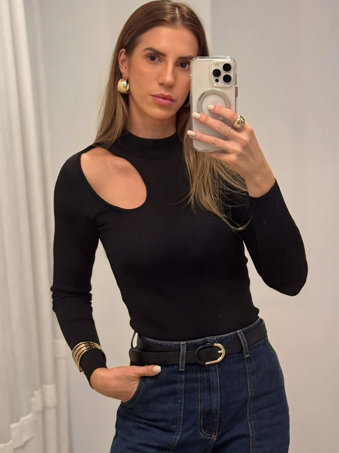 Fafá de blusa preta de gola alta com recorte no ombro, cinto e jeans